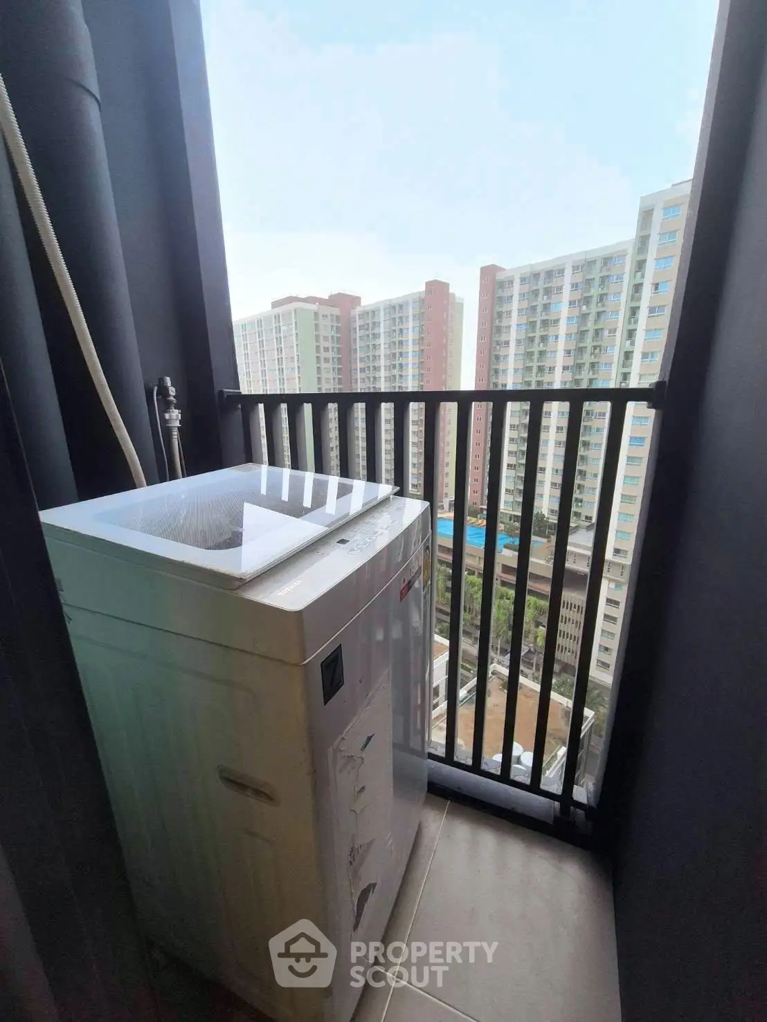 Compact balcony with washing machine and city view in modern apartment