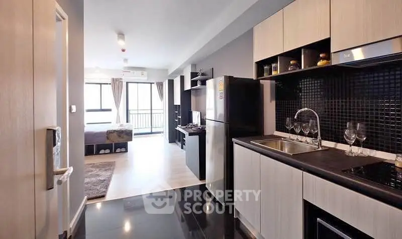 Modern apartment interior with sleek kitchen and open living area leading to a balcony.