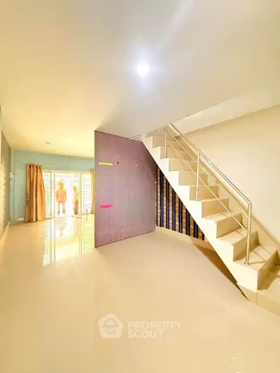 Spacious modern interior with staircase and large windows, perfect for family living.