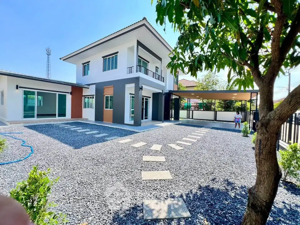 Modern two-story house with spacious gravel driveway and lush greenery, perfect for family living.