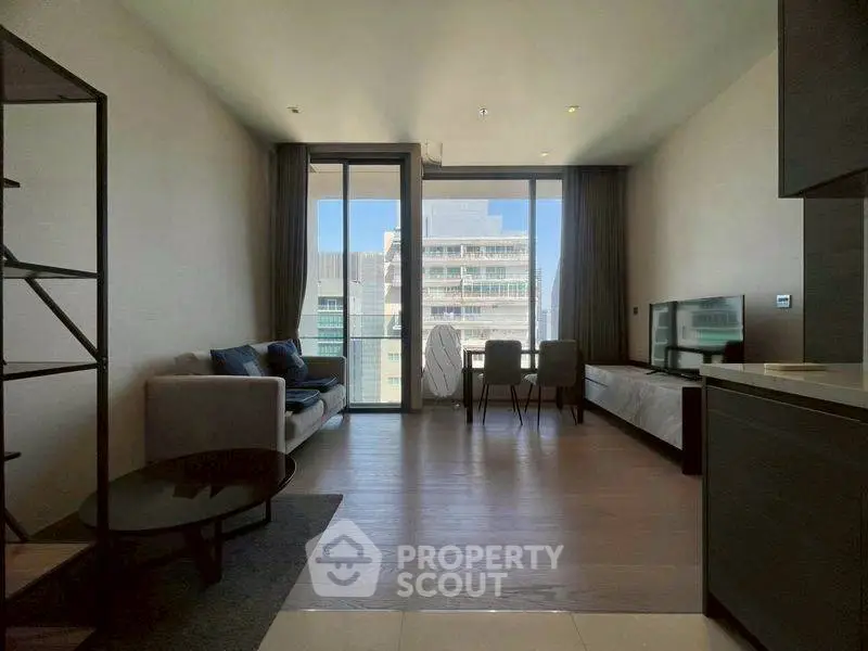 Modern living room with floor-to-ceiling windows and city view, featuring sleek furniture and open layout.