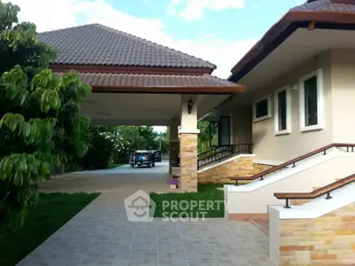 Charming single-story home with tiled roof and lush garden, featuring a spacious driveway and elegant entrance steps.