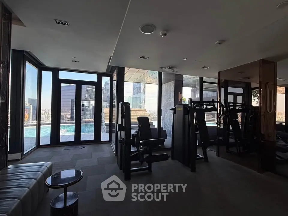 Luxurious gym with modern equipment and stunning city view near pool area.