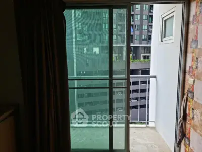 Modern apartment balcony with city view and sliding glass doors.