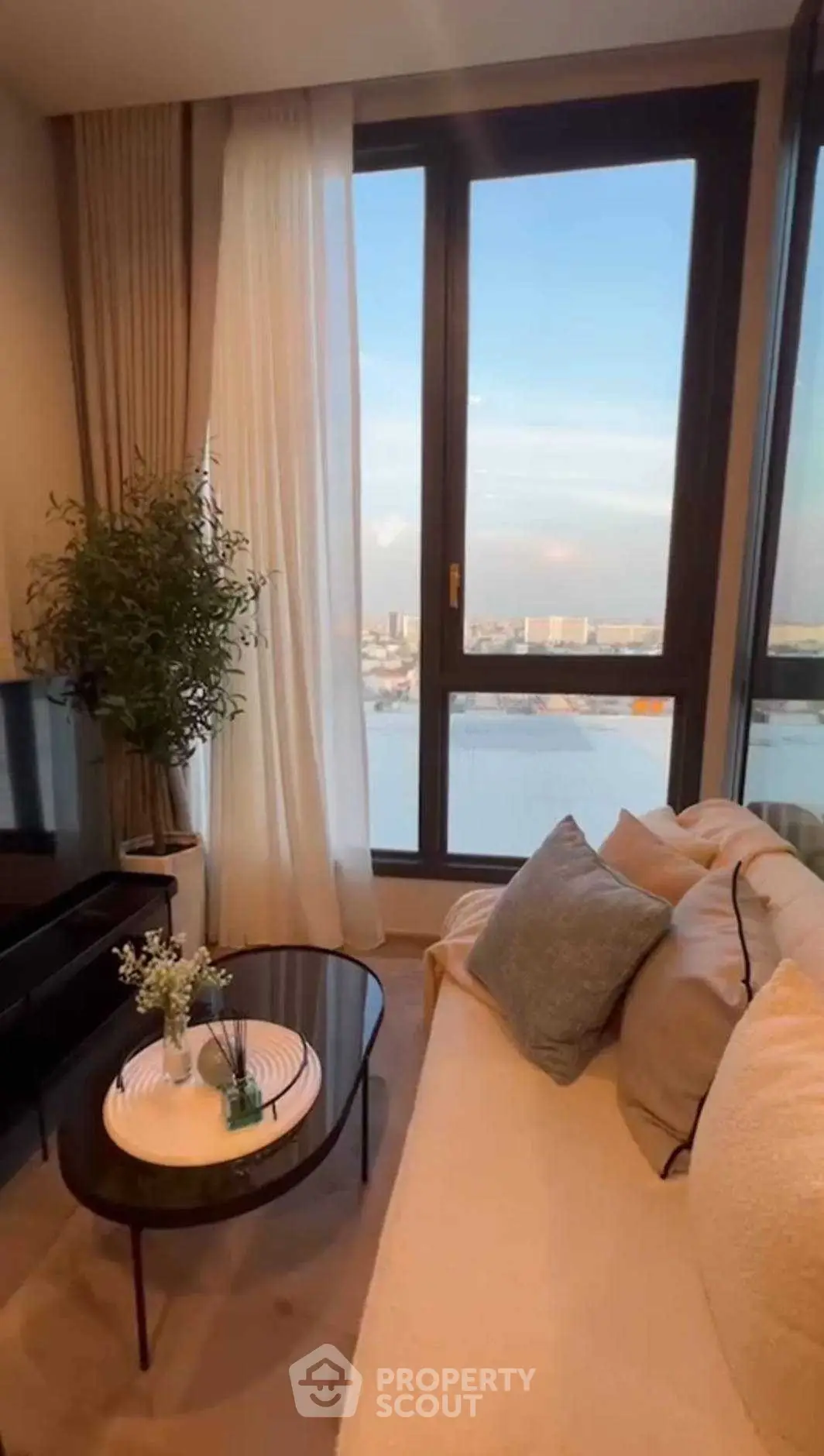 Stylish living room with large window offering stunning city view, cozy sofa, and elegant decor.