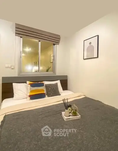 Cozy modern bedroom with stylish decor and large window for natural light.