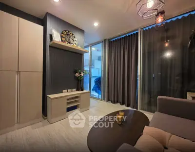 Modern living room with stylish decor and large windows leading to a balcony.