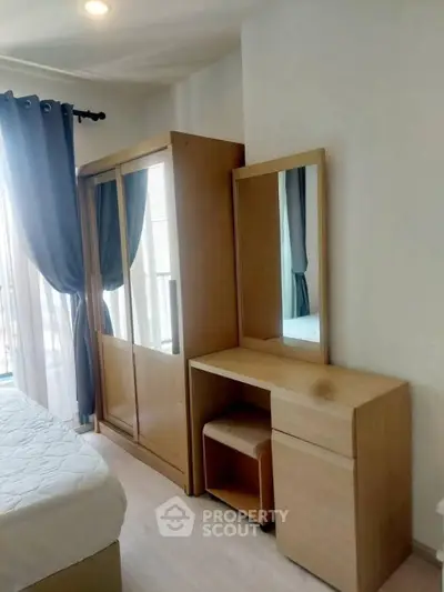 Cozy bedroom with modern wardrobe and dressing table, featuring natural light and elegant curtains.
