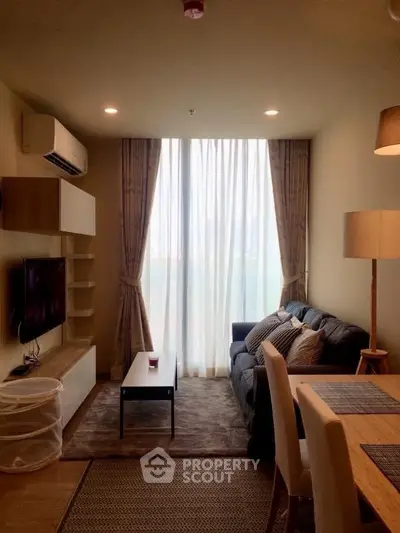 Cozy living room with modern decor, large window, and comfortable seating in a stylish apartment.