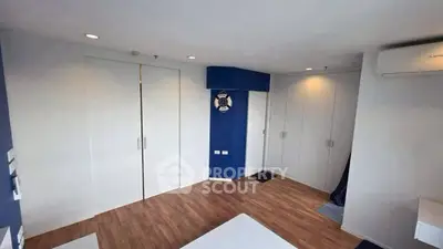 Spacious modern bedroom with sleek wooden flooring and ample closet space.