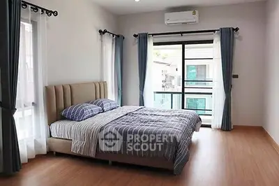 Spacious bedroom with modern decor and large windows for natural light.