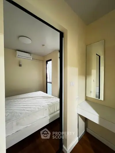 Cozy bedroom with air conditioning and wooden flooring, featuring a minimalist design and ample natural light.