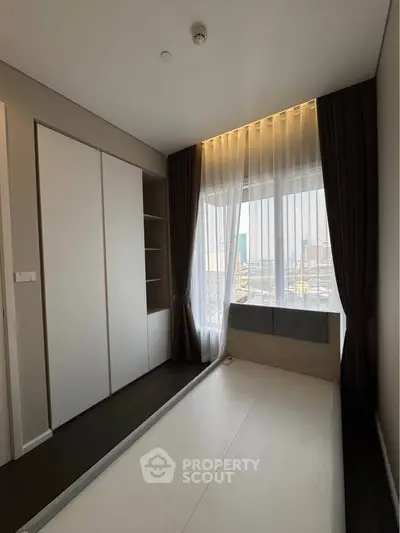 Modern bedroom with large window and built-in wardrobe, perfect for urban living.