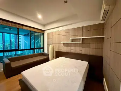 Modern bedroom with city view, featuring stylish wood paneling and cozy furnishings.