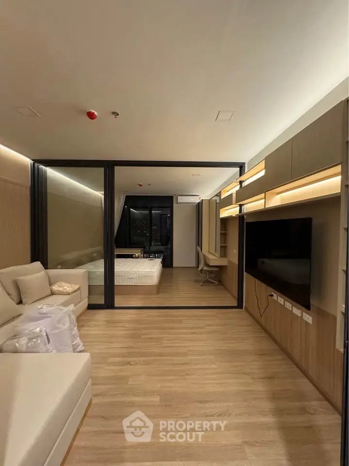Modern open-plan living room with cozy seating and stylish bedroom partition