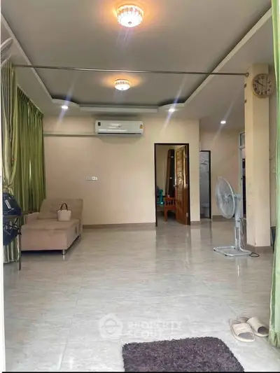Spacious living room with modern decor and air conditioning, featuring a comfortable sofa and elegant lighting.