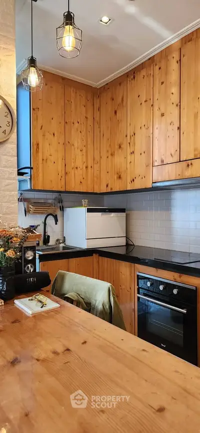 Charming kitchen with wooden cabinets and modern appliances, featuring a cozy open layout and stylish lighting.