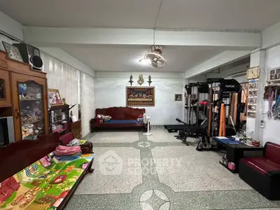 Spacious living room with gym equipment and cozy seating area, perfect for relaxation and fitness.