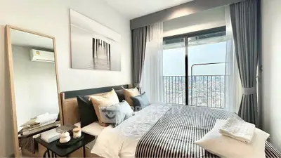 Modern bedroom with city view, stylish decor, and ample natural light.
