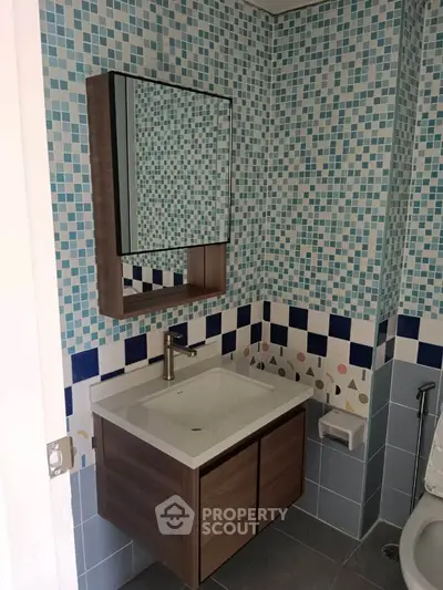 Modern bathroom with stylish mosaic tiles and sleek vanity unit.