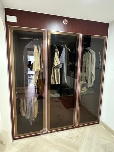 Spacious walk-in closet with elegant glass doors and ample storage space.