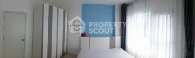 Bright and spacious bedroom with modern wardrobe and large window.