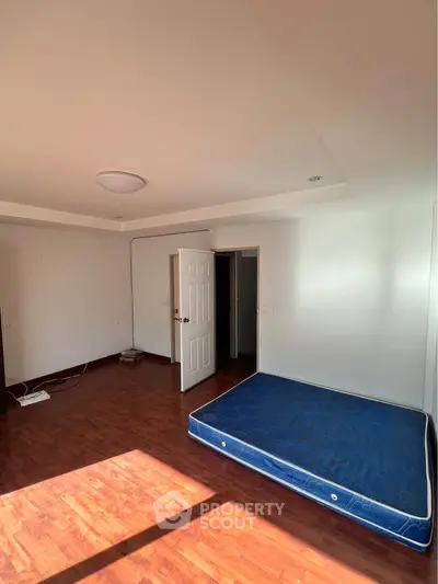 Spacious empty bedroom with wooden flooring and natural light