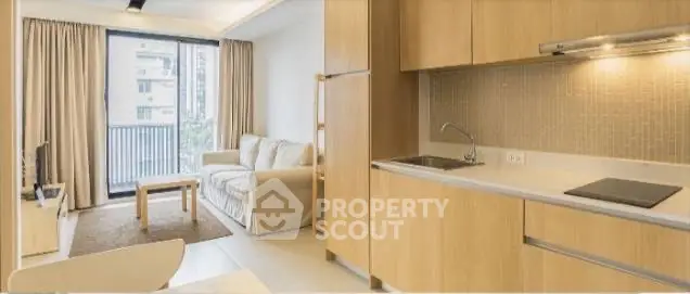 Modern open-plan living room with kitchen, featuring sleek wooden cabinetry and a cozy seating area.
