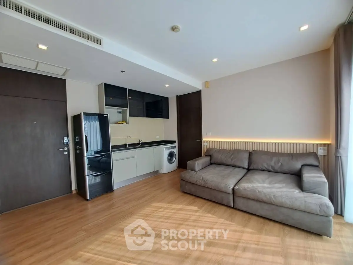 Modern living room with sleek kitchen and cozy sofa in open layout apartment.