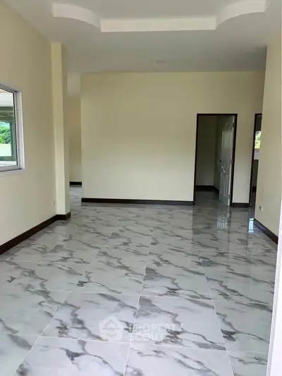 Spacious empty room with elegant marble flooring and neutral walls, perfect for customization.