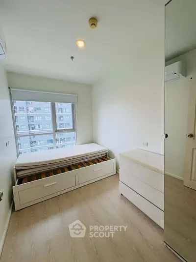 Bright and cozy bedroom with large window and modern furnishings in a high-rise apartment.