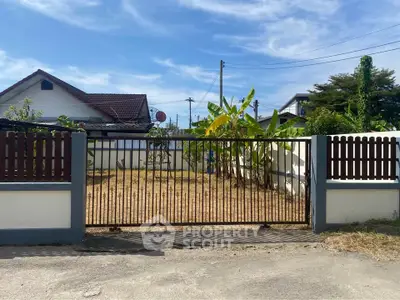 Charming suburban home with spacious front yard and secure gated entrance.