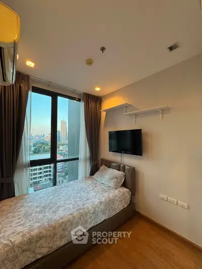 Cozy bedroom with city view, featuring a single bed and wall-mounted TV, perfect for urban living.