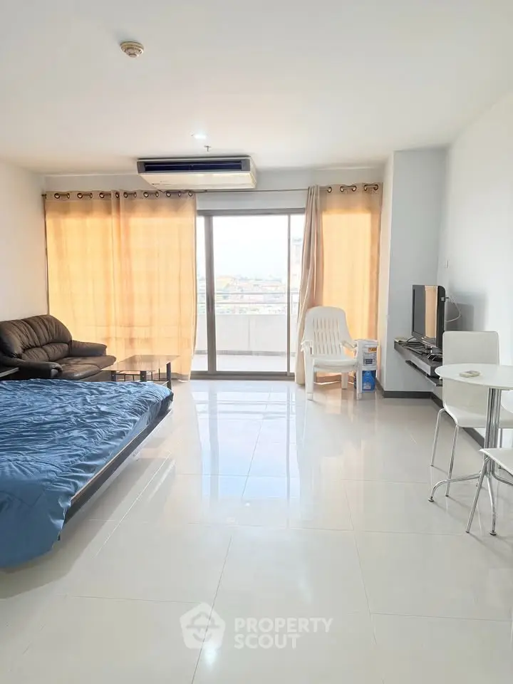 Spacious modern living room with large windows and city view, featuring cozy seating and sleek decor.