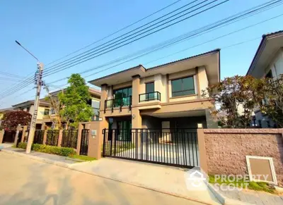 Modern two-story house with gated entrance and landscaped garden in a suburban neighborhood.