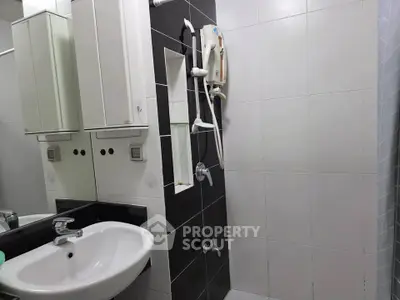 Modern bathroom with sleek black and white tiles, featuring a stylish sink and shower area.