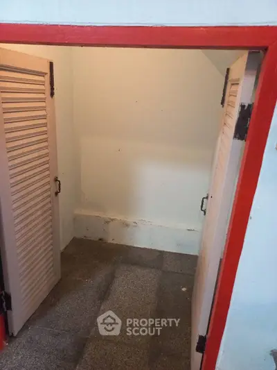 Compact storage space with red trim and louvered doors, ideal for organizing essentials.