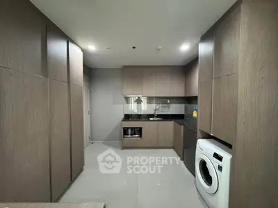 Modern kitchen with sleek cabinetry and built-in washing machine, perfect for urban living.