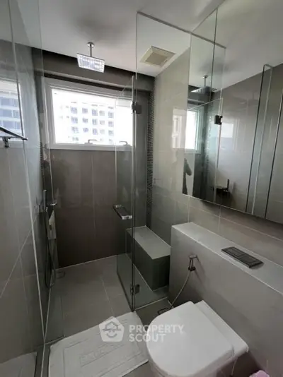 Modern bathroom with glass shower and sleek fixtures in urban apartment.