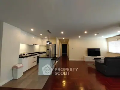 Spacious open-layout living room with modern kitchen and hardwood floors