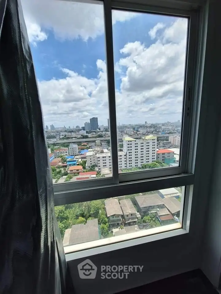 Stunning cityscape view from high-rise apartment window with clear blue skies.