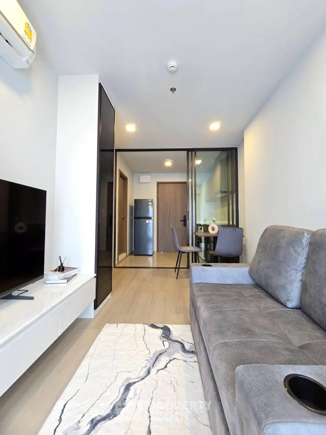 Modern living room with sleek furniture and open layout, featuring a cozy gray sofa and stylish decor.