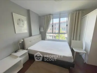 Cozy bedroom with large window and modern furnishings in a bright apartment.