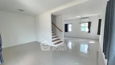 Spacious modern living room with sleek tile flooring and staircase, featuring large windows for natural light.