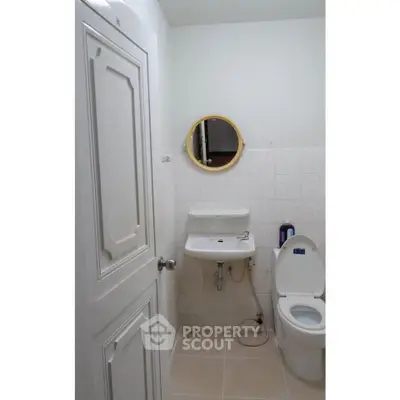 Compact bathroom with modern fixtures and round mirror