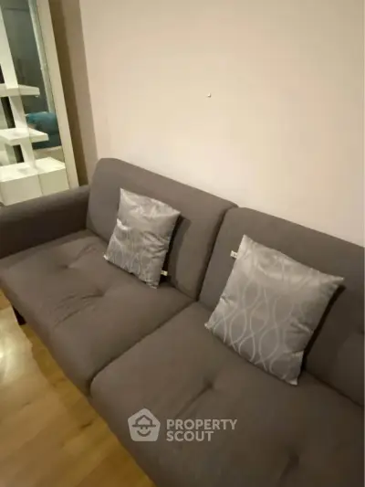 Cozy living room with modern gray sofa and stylish cushions, perfect for relaxation.