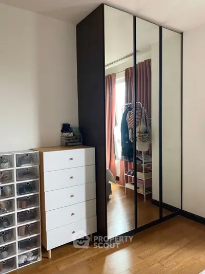 Spacious bedroom with mirrored wardrobe and organized storage solutions.