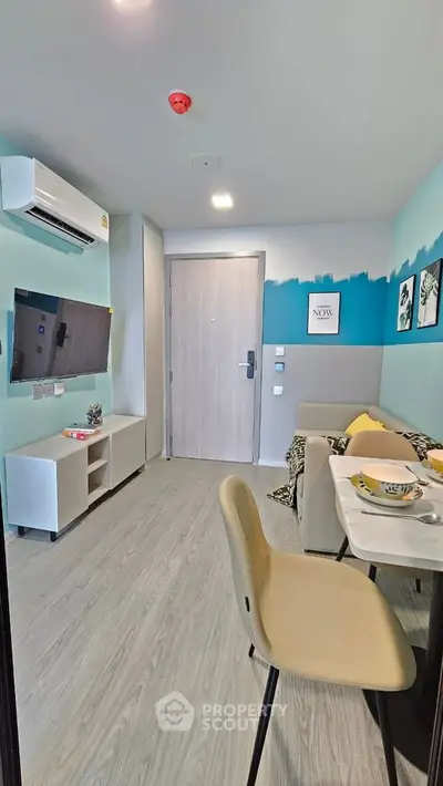 Modern living room with stylish decor and open layout, featuring a wall-mounted TV and cozy seating area.