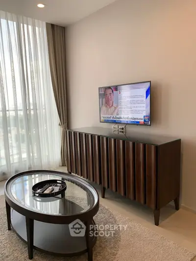 Modern living room with stylish furniture and mounted TV, featuring elegant curtains and natural light.