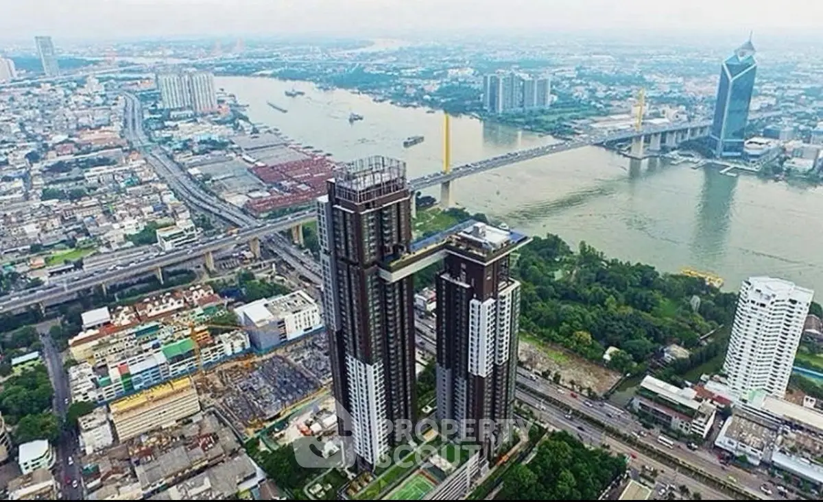 Stunning aerial view of modern high-rise buildings by the river in a bustling cityscape.